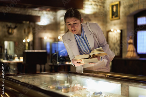 Portrait of adorable woman reading book while standing at museum exhibit