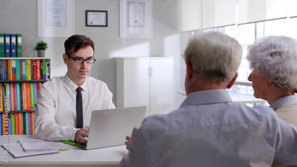 Young broker with laptop advise elderly couple