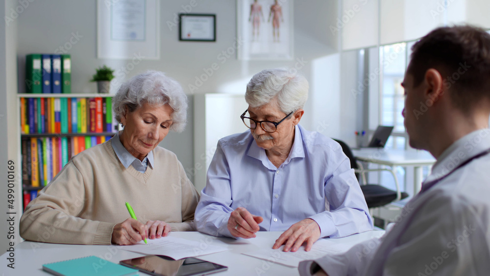 Obraz premium Senior couple sign document in doctor office