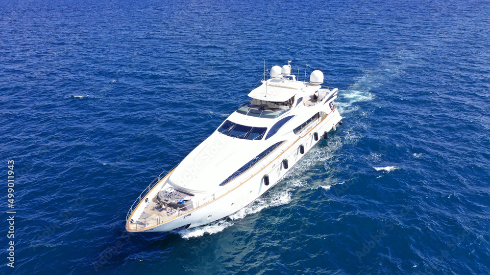 Aerial drone photo of small luxury yacht cruising in deep blue sea near Aegean island, Greece