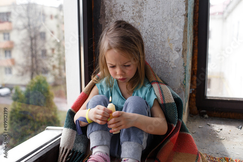 Obraz na płótnie a little Ukrainian girl prays for the freedom of Ukraine and holds a candle in her hands