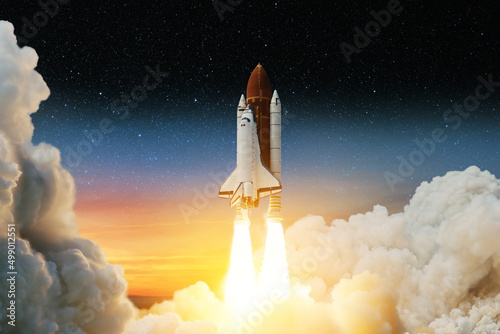 Fototapeta Naklejka Na Ścianę i Meble -  Spaceship lift off. Space shuttle with smoke and blast takes off into space on a background of sunset and the starry sky. Successful start of a space mission. Elements of this image furnished by NASA.