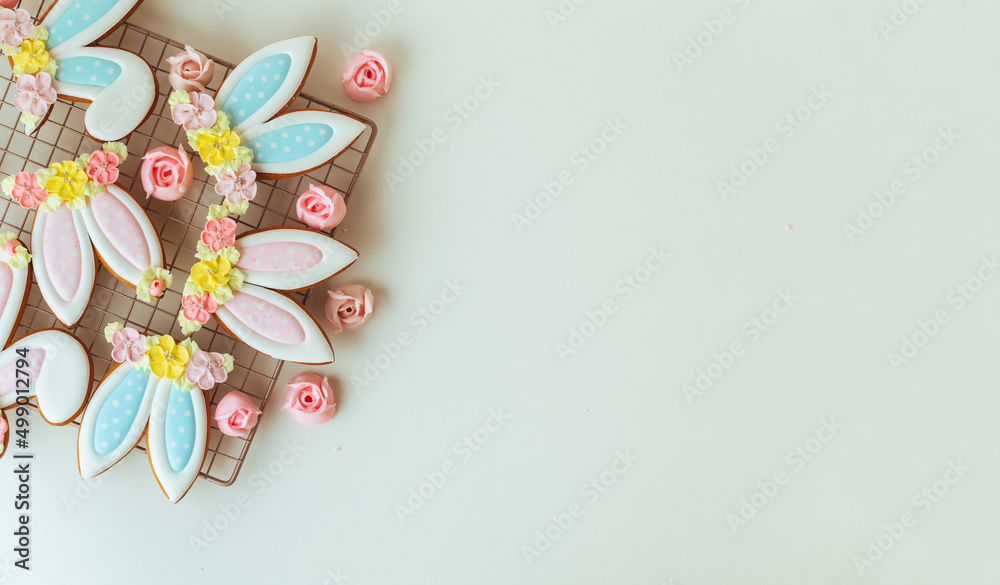 Gingerbread cookies in the shape of cute Easter bunny ears decorated with festive icing and flowers on the white background. Flat lay