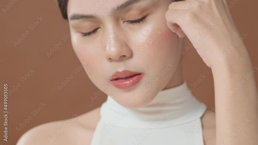 A young woman with beautiful face smiling , touching her face over brown background , beauty skin care concept A young woman with beautiful face smiling , touching her face over brown background , beauty skin care concept