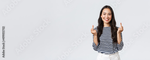 Lifestyle, beauty and fashion, people emotions concept. Unbothered and careless young happy smiling woman dont give a damn, showing middle fingers and feeling good, white background photo