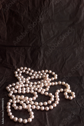 Feminine desktop mockup with pearls on black paper background with copy space.