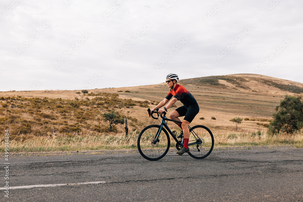 Side view of professional cyclist practicing on a countryside road against a hill Side view of professional cyclist practicing on a countryside road against a hill