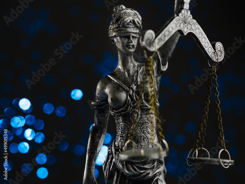 Bronze figurine of Themis - the goddess of justice on a blue background with twinkling lights. Symbol of law  justice  independence. The rule of law. Close-up.