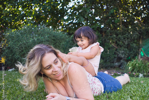 Little girl climbed on the back of a woman in the grass