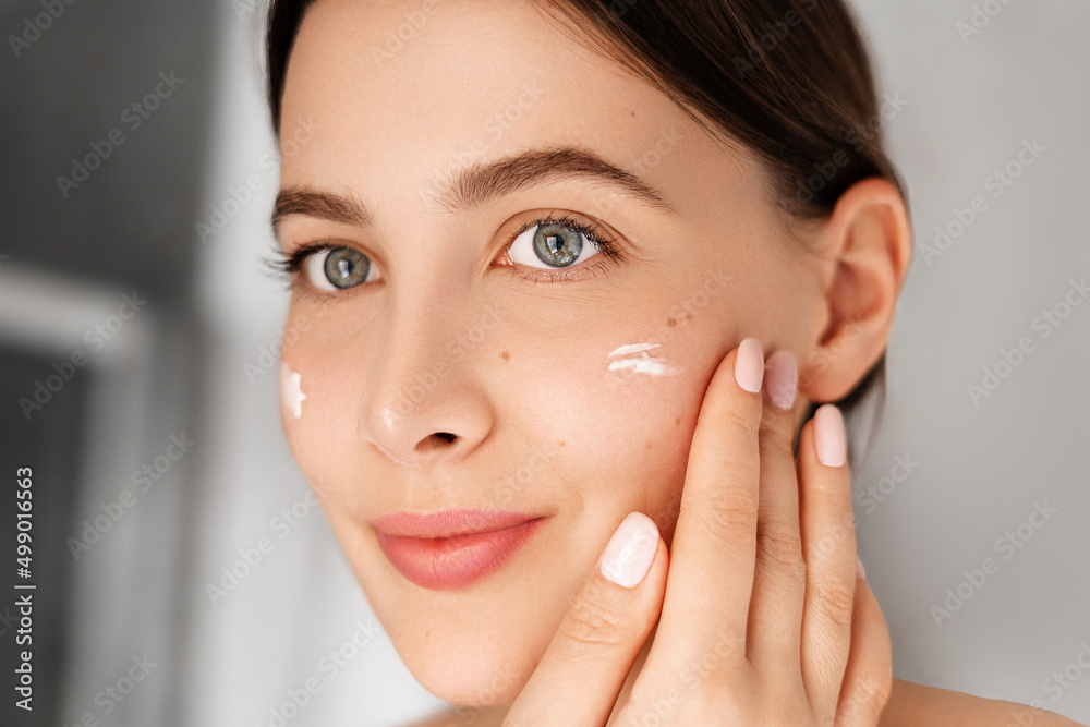 Applay cream. Beauty portrait of young woman caring about skin at home Applay cream. Beauty portrait of young woman caring about skin at home