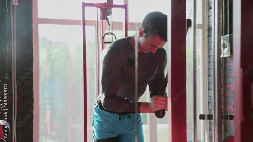 Handsome athletic man trains triceps on machine at gym Handsome athletic man trains triceps on machine at gym