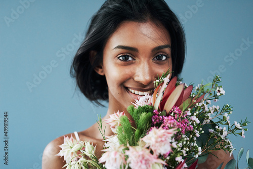 Flowers are a surefire way to grab a womans attention. Cropped shot of a beautiful young woman posing with a bouquet of flowers. photo