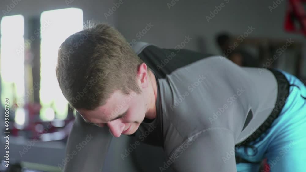 Close up of handsome athletic man performing One-arm dumbbell row at gym