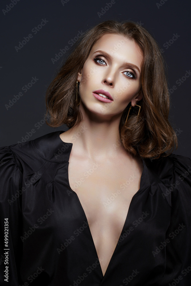 Studio shot of sexy brunette woman in black dress who isolated on dark background. Fashion photo