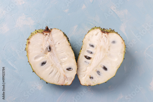Slika na platnu Two halves of ripe soursop on light blue background, top view