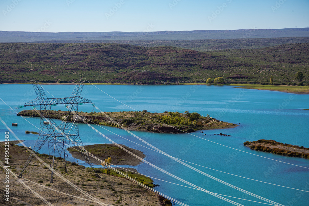 Patagonia landscape with a high-voltage hydroelectric power line on the banks of the Limay river, El Chocon, Neuquen Province, Argentina