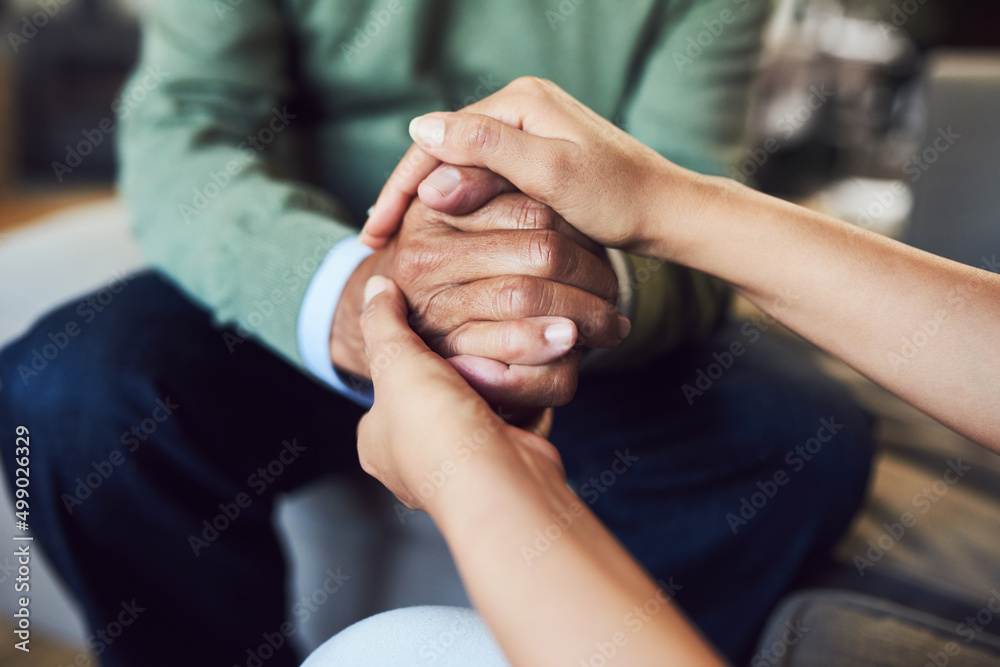 Her support means everything to me. Shot of an unrecognizable senior man holding hands with his daughter while sitting on a couch at home.