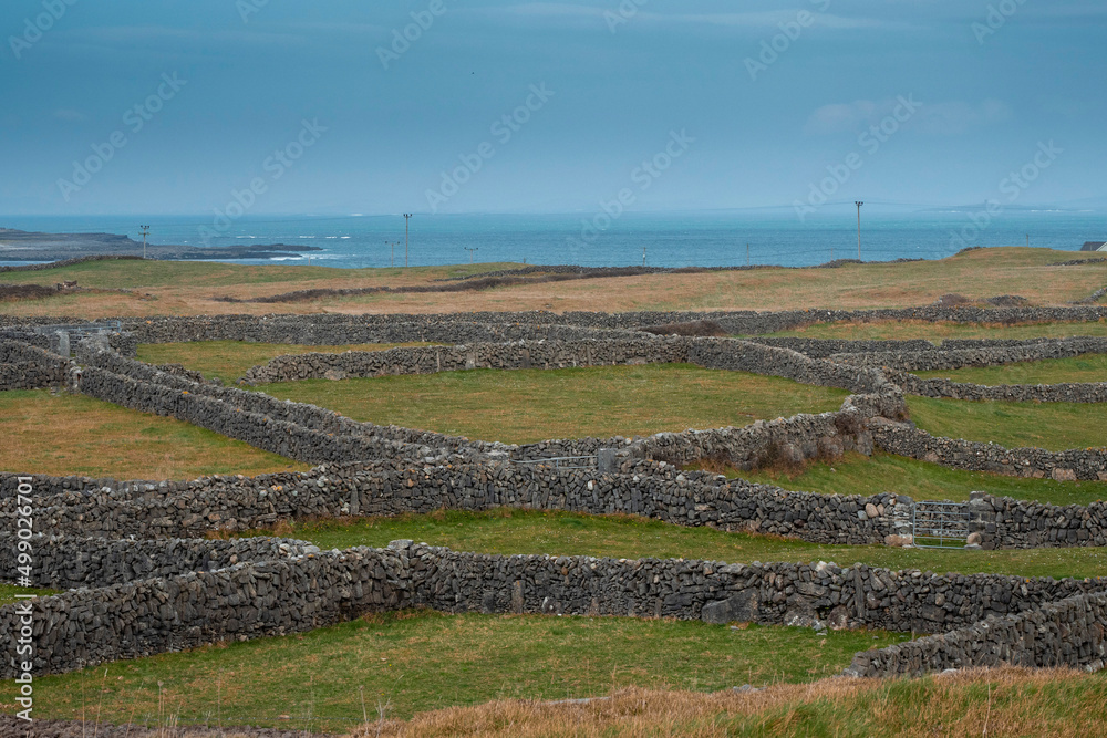 Nature scene of Inishmore,, Aran island. Rough stone terrain. Blue cloudy sky. Maze of dry stone walls. Popular tourist area with amazing nature view. Nature scene of Inishmore,, Aran island. Rough stone terrain. Blue cloudy sky. Maze of dry stone walls. Popular tourist area with amazing nature view.