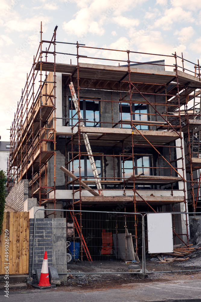 Town residential house building. Modern home construction site with scaffolding. Nobody. Town residential house building. Modern home construction site with scaffolding. Nobody.
