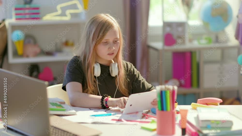 modern girl in grey shirt with tablet PC homeschooling at home in sunny day. modern girl in grey shirt with tablet PC homeschooling at home in sunny day.