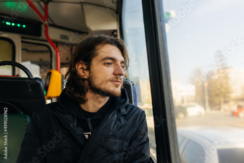 A young man rides in a trolleybus and looks out the window © inna
