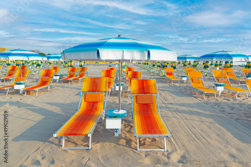 Blue umbrellas and chaise lounges on the beach of Rimini in Italy