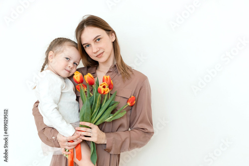 Happy daughter congratulates mom with tulips. Portrait. Looking at camera