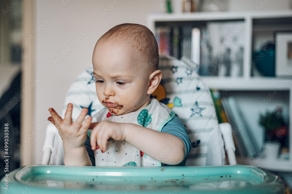 Baby boy eating chocolate while sitting in a dinning chair Baby boy eating chocolate while sitting in a dinning chair