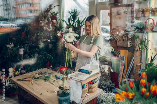 Female florist making a fresh flowers bouquet in a flower shop