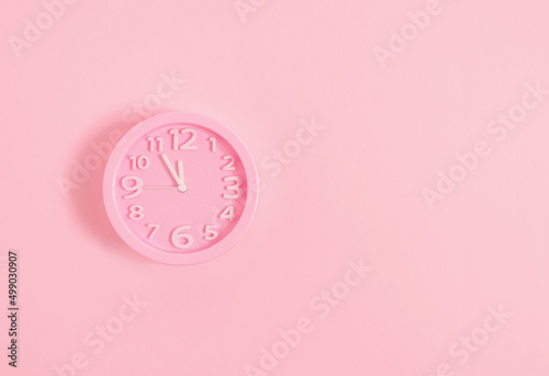 Pink alarm clock on pink painted wall. Minimal time concept. Chrismas eve or new year idea