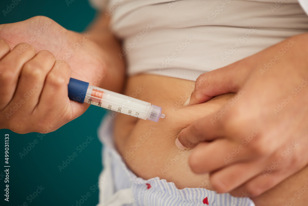 The body knows when insulin is required. Closeup shot of an unrecognizable woman injecting herself in the stomach with insulin at home. The body knows when insulin is required. Closeup shot of an unrecognizable woman injecting herself in the stomach with insulin at home.