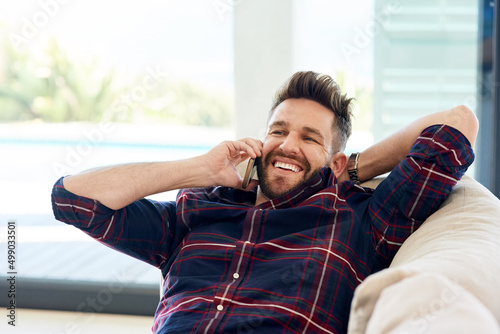 Wanna come over and chill. Shot of a young man using his phone while relaxing on the sofa at home.