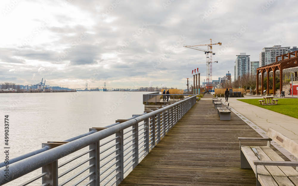 Pier and walkway by riverside. Beautiful river park in New Westminster in overcast day.
