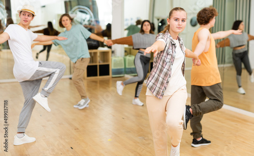 Portrait of teenage girl learning to dance vigorous cheerful lindy hop in pair with boy in choreography class.