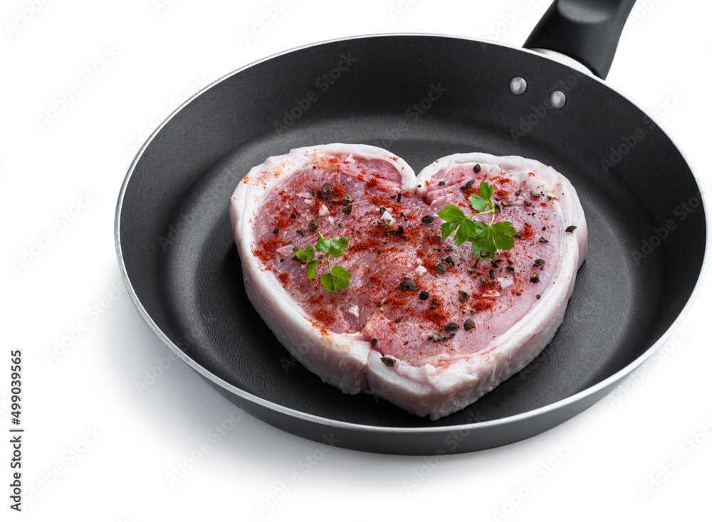 Heart shaped raw fresh pork slices with parsley and herbs on frying pan isolated on white Heart shaped raw fresh pork slices with parsley and herbs on frying pan isolated on white