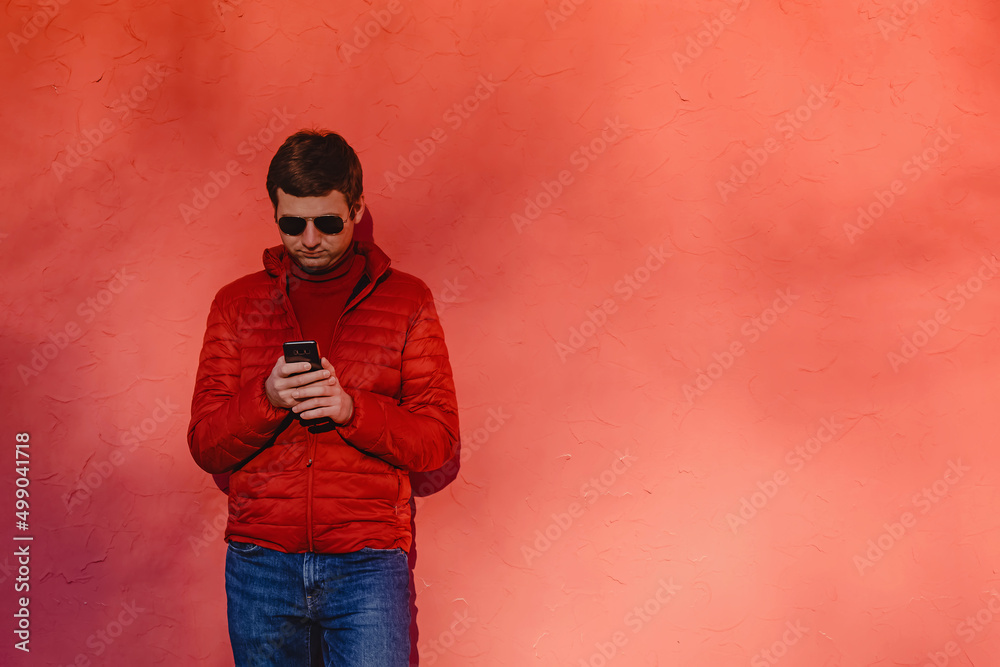 Young man in red sweater, using his smart phone
