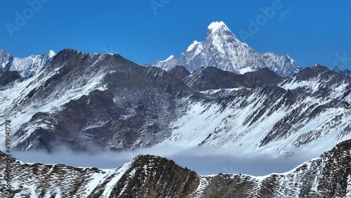 Aerial landscape of snow mountain peak of Mount Siguniang at Sichuan China snow mountain with mist floating under blue sky ,camera panning right photo