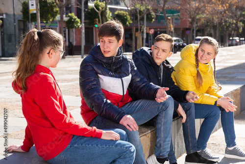 Group of modern teenagers hanging out on streets of city on warm spring day.. © JackF