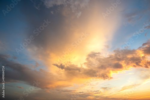 Fototapeta Naklejka Na Ścianę i Meble -  Dramatic cloudy sunset landscape with puffy clouds lit by orange setting sun and blue sky.