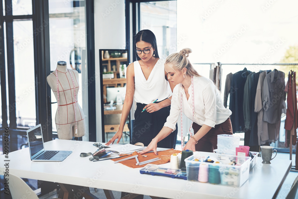 Obraz premium I need your professional opinion. Shot of two young fashion designers working together in a workshop.