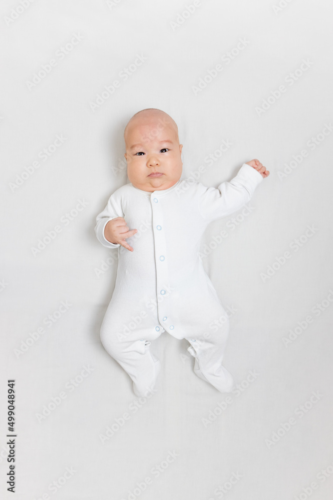 Asian baby in white clothes lies on a white bed. mokcup.Selective focus Asian baby in white clothes lies on a white bed. mokcup.Selective focus