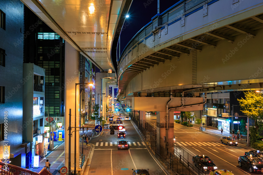 Overhead view of cars on wide road under elevated tracks at night Overhead view of cars on wide road under elevated tracks at night