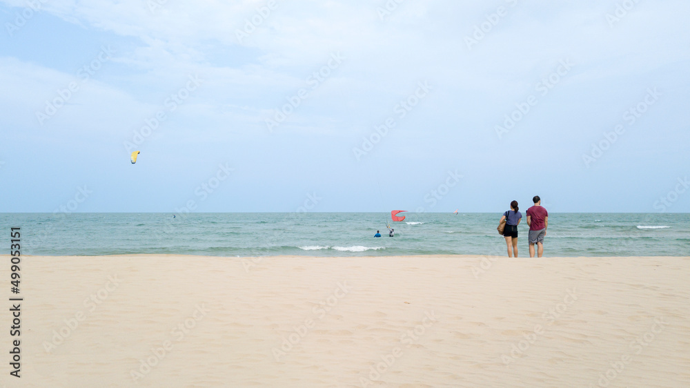 Travelers stand and look around the beach.