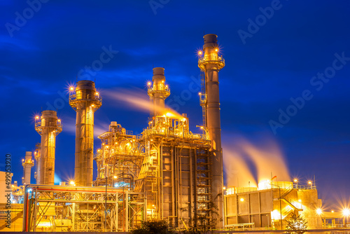 Oil refinery plant chemical factory and power plant with many storage tanks and pipelines at sunset.