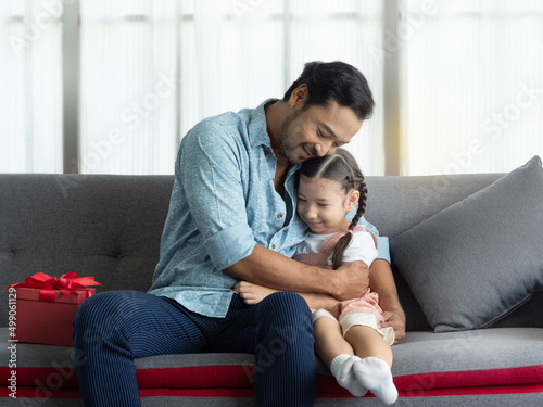 Handsome Asian dad giving cute daughter a big hug afther getting gift for speicial day. Father's day or Birthday concept. photo