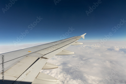 Passenger airplane wing against blue sky and clouds