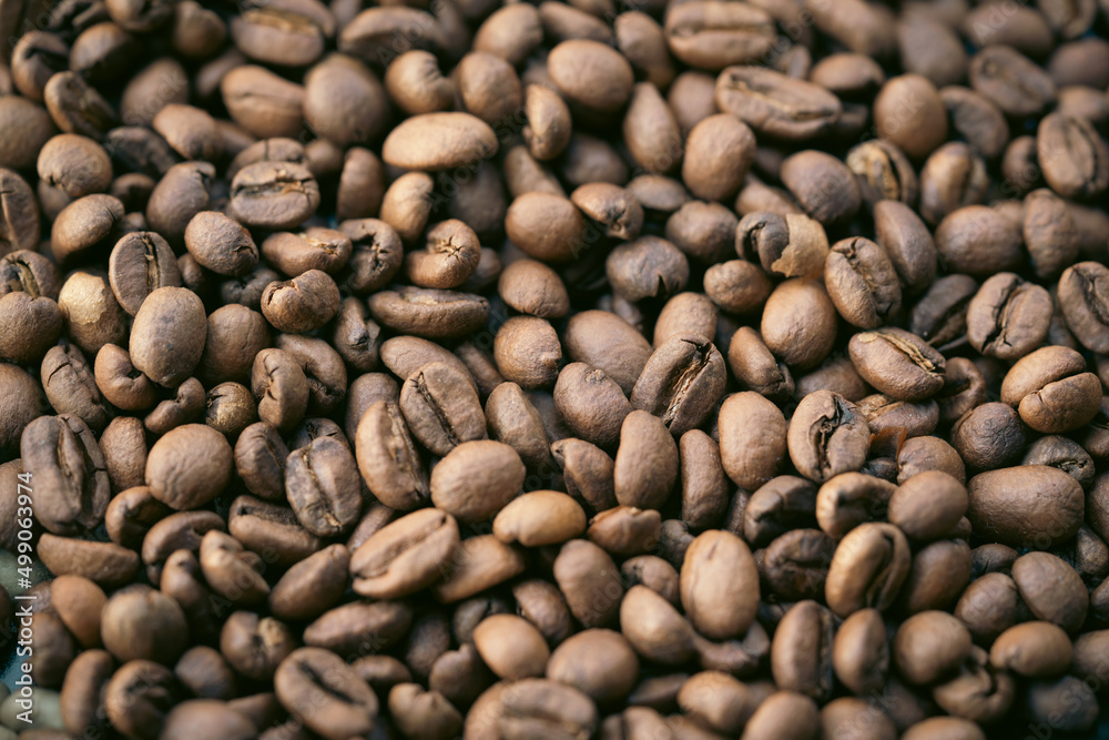 A pile of natural brown roasted coffee beans. A pile of natural brown roasted coffee beans.