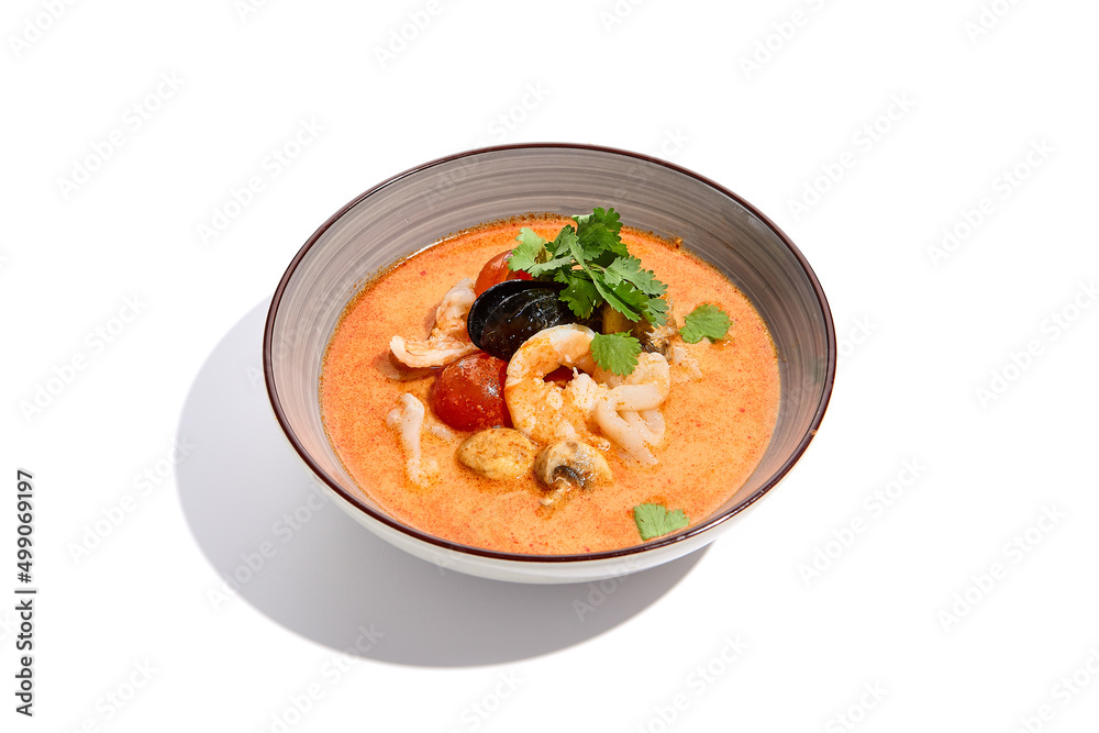 Traditional asian soup - tom yam with prawn and coconut milk isolated on white background. Tom yam kung with seafood and coriander in gray bowl on white background.