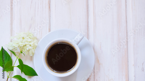 White cup with coffee and hydrangea flower