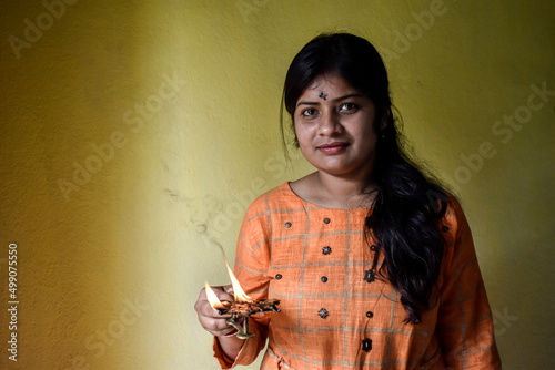 Indian woman performing worship along with lighting oil lamp photo